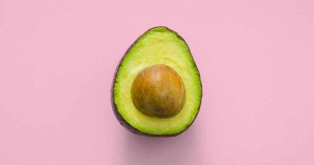 Fresh avocado halves with green flesh and a seed